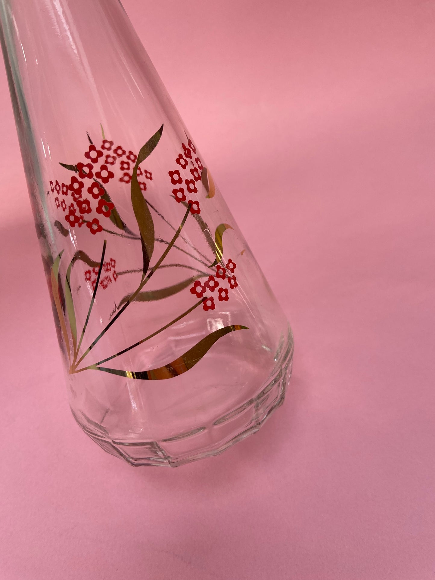 Vintage glass carafe with red flower pattern and gold leaf.