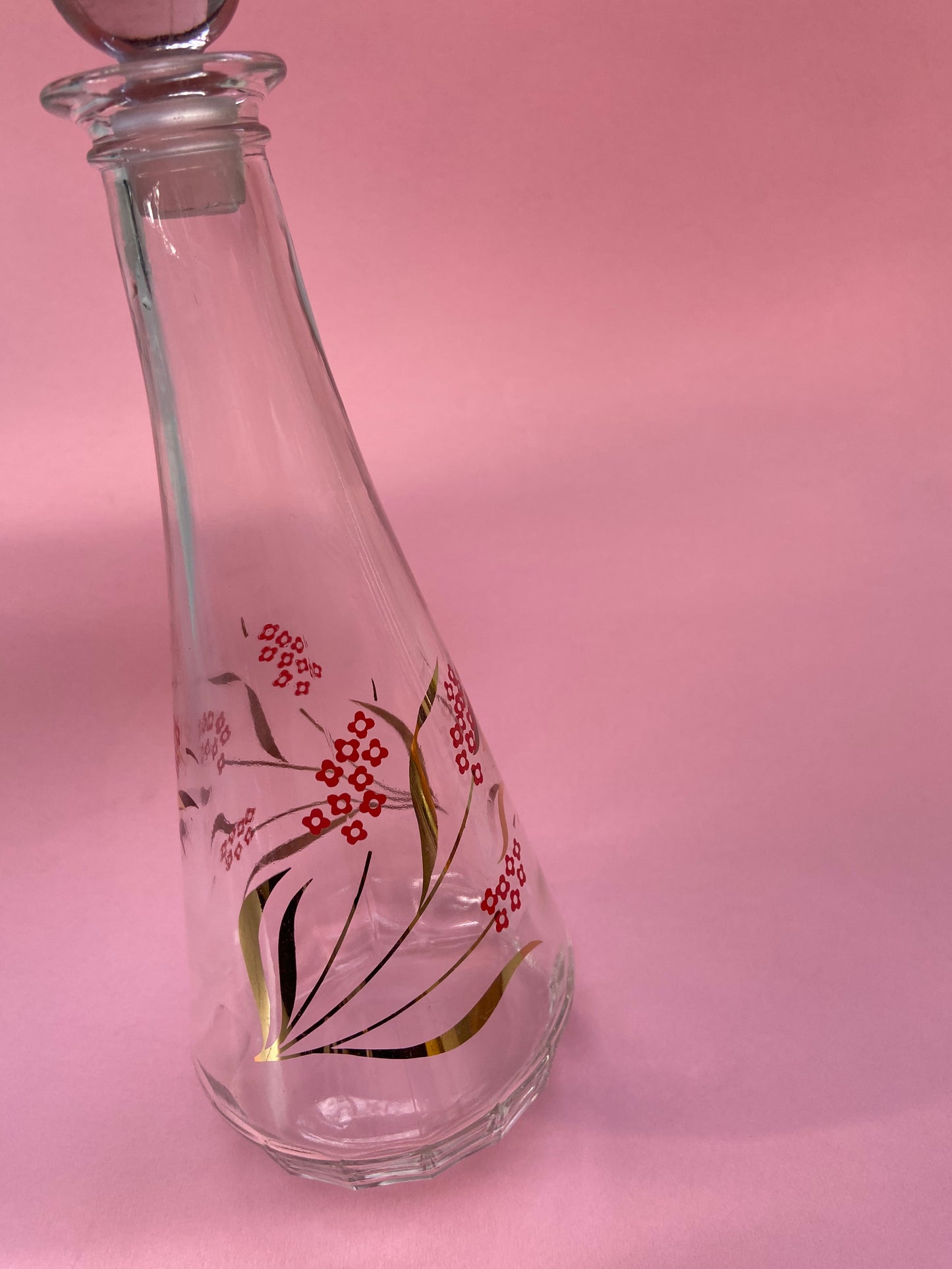 Vintage glass carafe with red flower pattern and gold leaf.