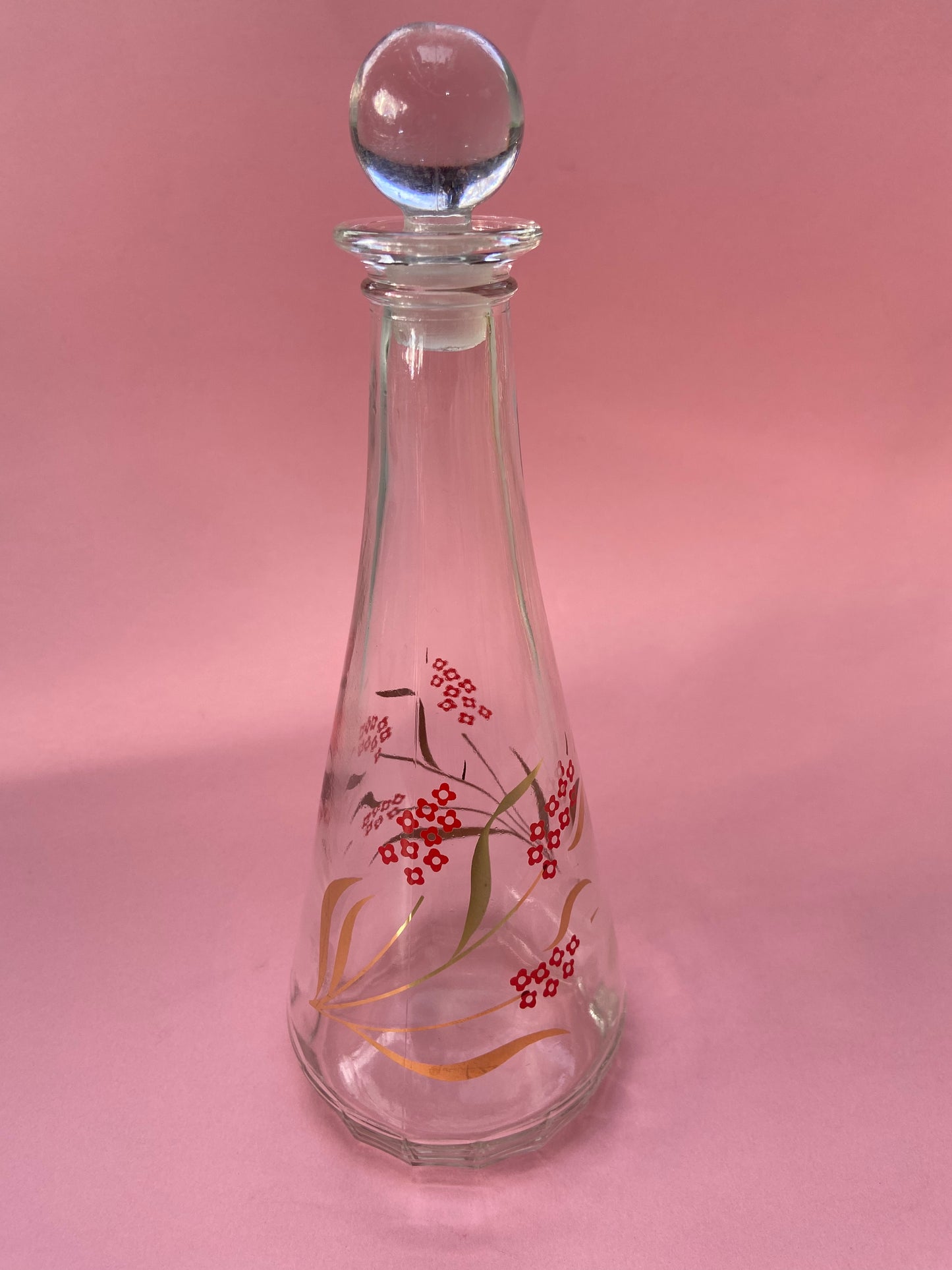 Vintage glass carafe with red flower pattern and gold leaf.