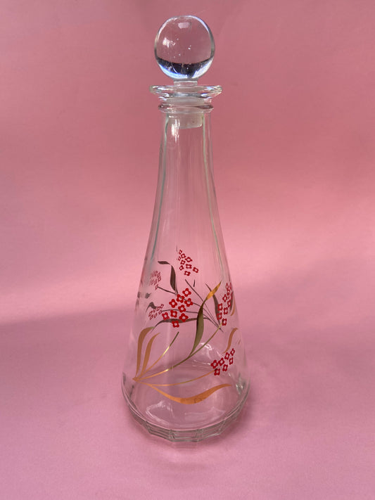 Vintage glass carafe with red flower pattern and gold leaf.