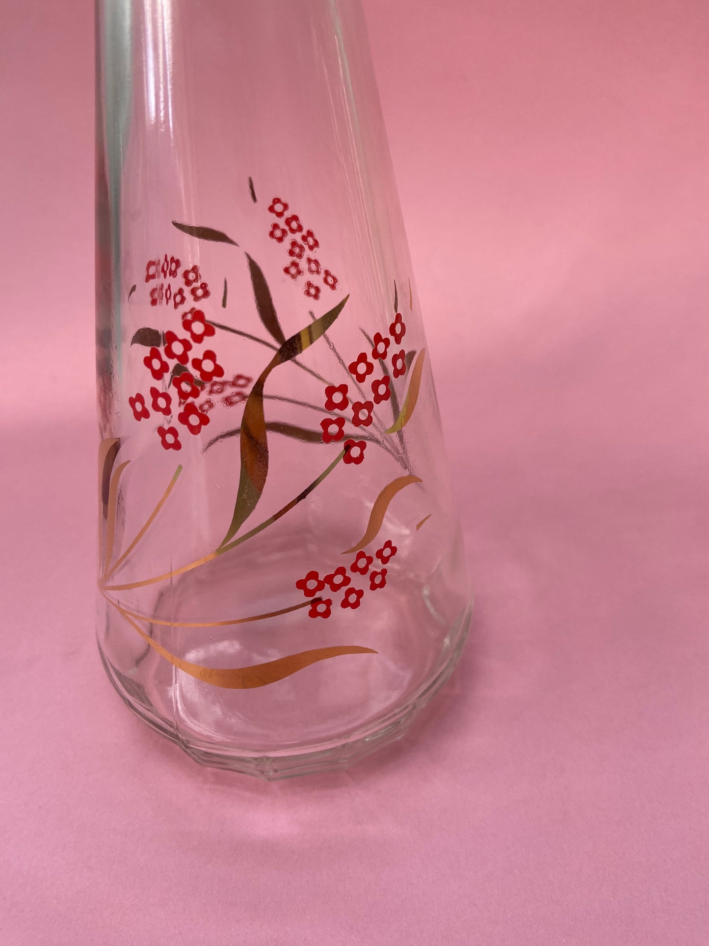 Vintage glass carafe with red flower pattern and gold leaf.