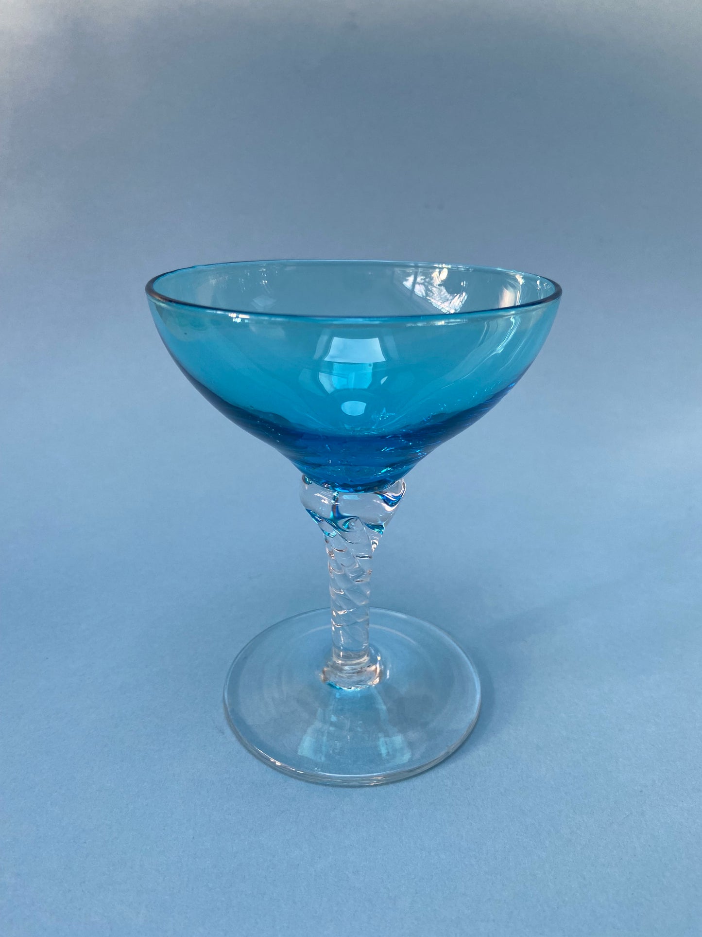 Transparent twisted foot cocktail glass and blue glass