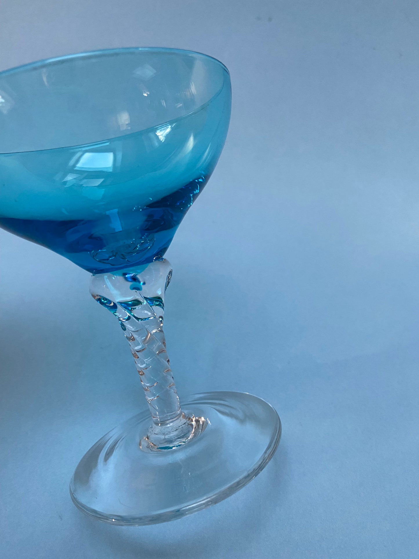 Transparent twisted foot cocktail glass and blue glass