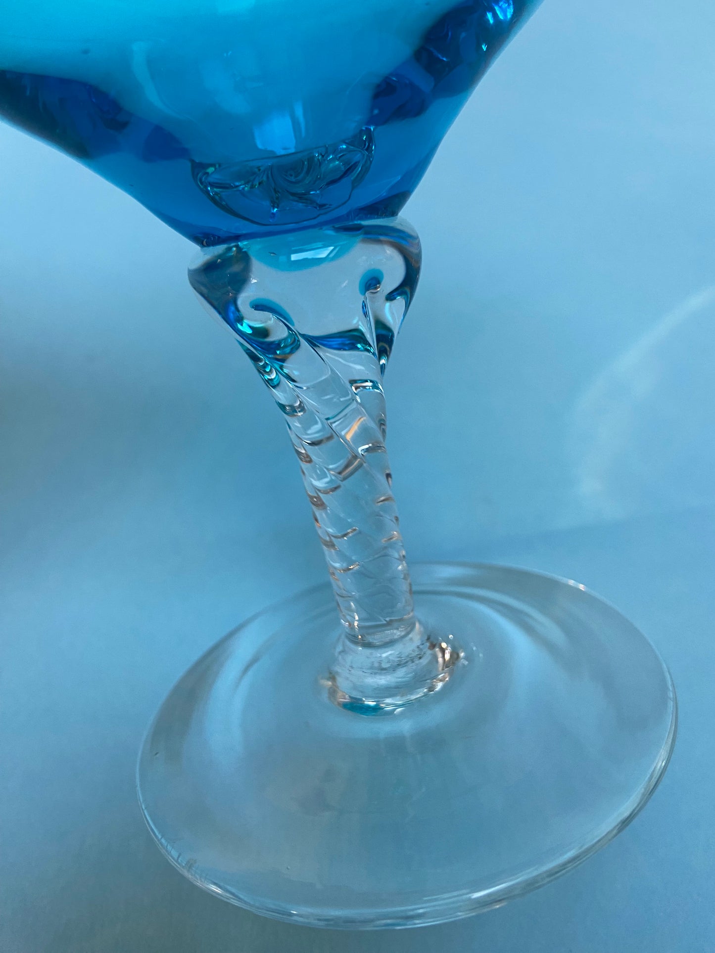 Transparent twisted foot cocktail glass and blue glass