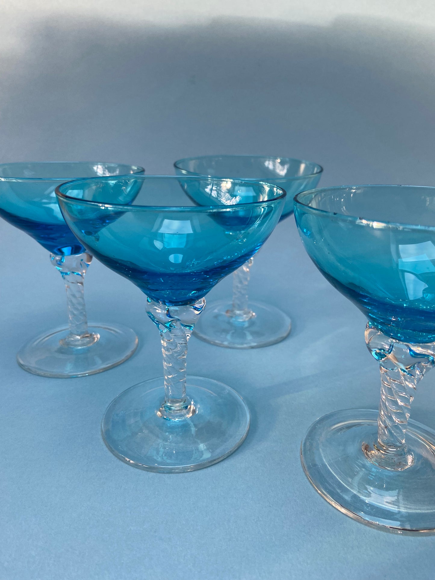 Transparent twisted foot cocktail glass and blue glass